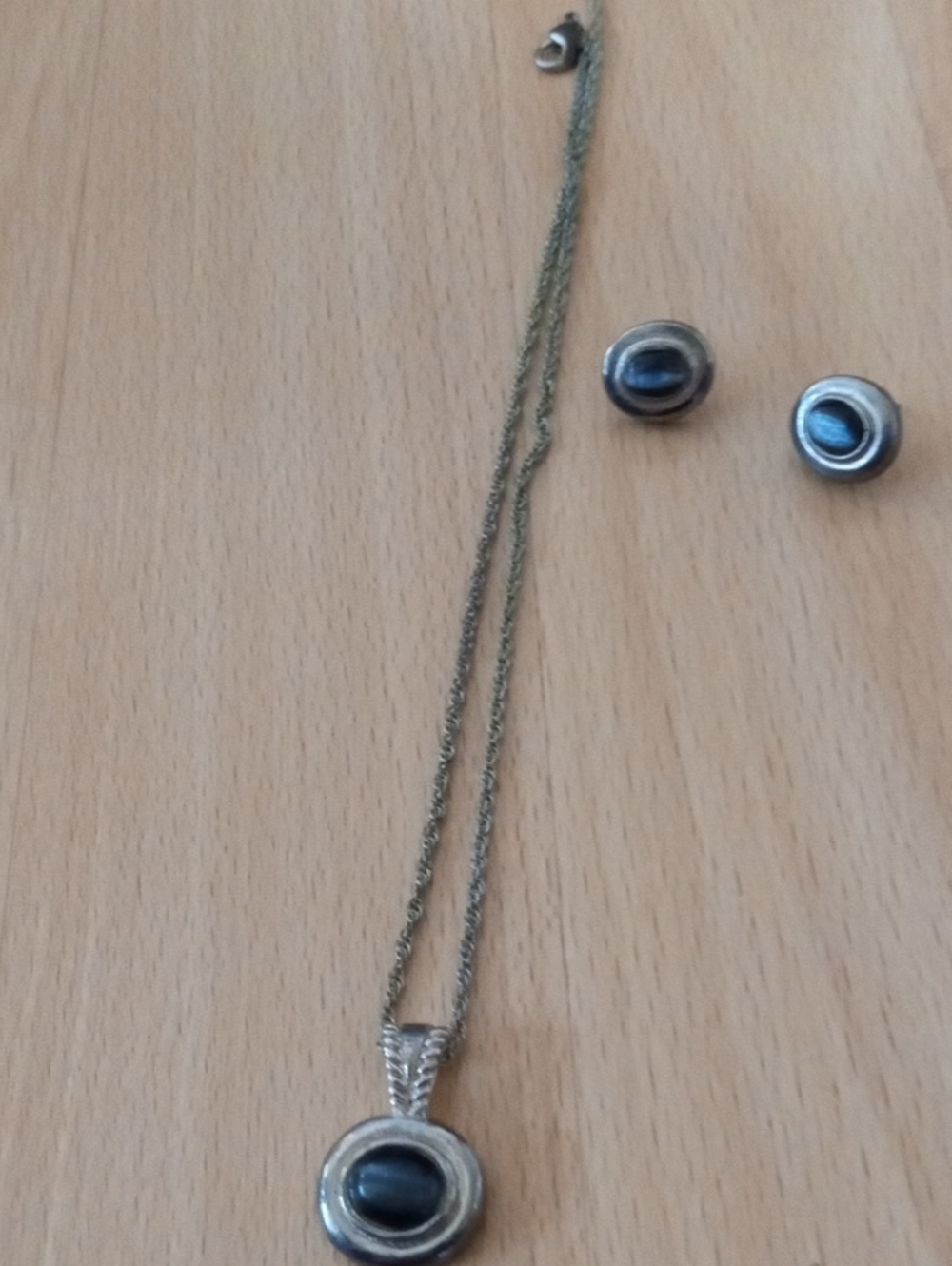 $10>> a silver-toned pendant necklace featuring a dark, chatoyant gemstone